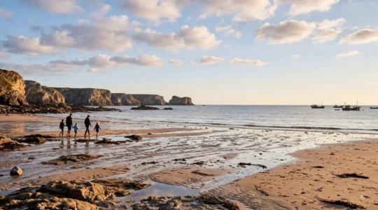 Vue panoramique d'une côte française sauvage avec famille explorant les rochers à marée basse