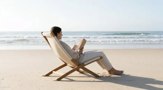 Personne lisant confortablement sur une chaise de plage ergonomique avec le sable et la mer en arrière-plan