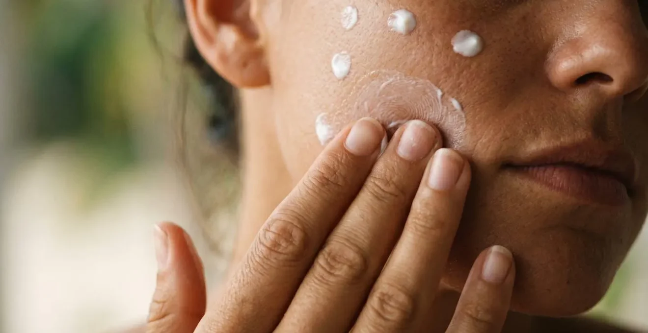 Application méthodique de crème solaire sur le visage en plusieurs zones pour une couverture parfaite.