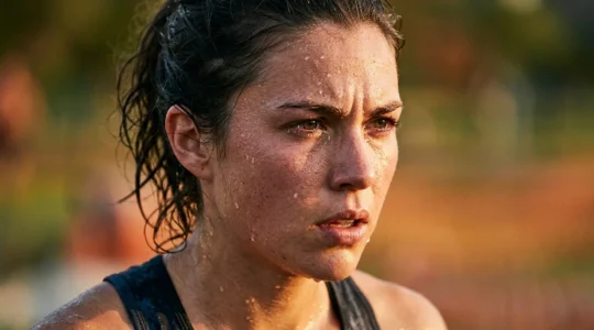 Coureur en plein effort sous le soleil estival avec de la transpiration visible sur le visage