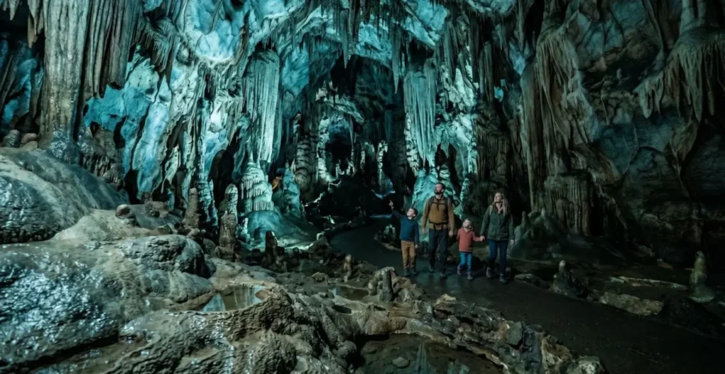 Famille explorant une grotte fraîche avec formations rocheuses spectaculaires